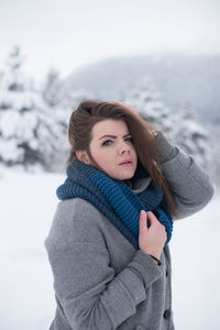 Portrait of woman standing against snow during winter