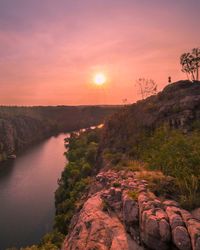 Scenic view of river and mountains against sky at sunset