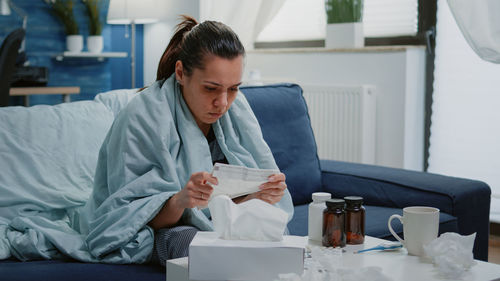 Ill woman sitting on sofa at home