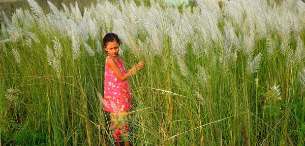 Girl standing amidst grass on field