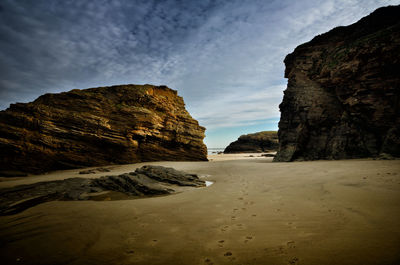 Rock formations on beach against sky