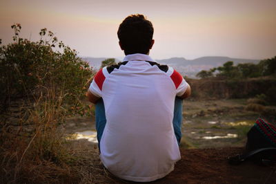 Rear view of a man with woman standing at sunset