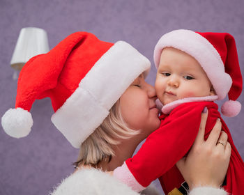 Mother wearing santa hat embracing son at home