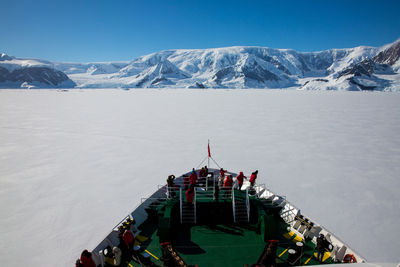 High angle view of people in boat on frozen sea against clear blue sky
