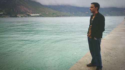 Young man looking at sea against mountain