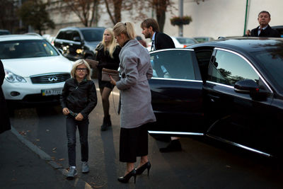 Full length of father and daughter standing on car