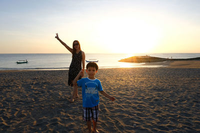 Full length of woman on beach against sky during sunset