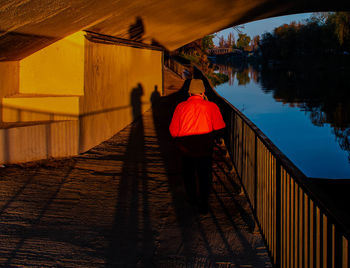 Rear view of people standing on bridge over lake