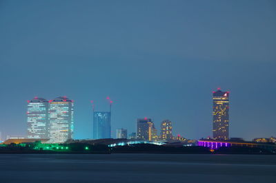 Illuminated buildings against clear sky at night