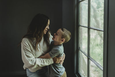 Mid level view of mother and son looking at each other next to window