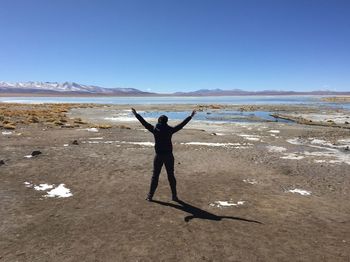 Man with arms wide on riverbank enjoying freedom