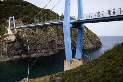 Low angle view of people on bridge over sea