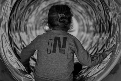 Rear view of girl sitting at play equipment