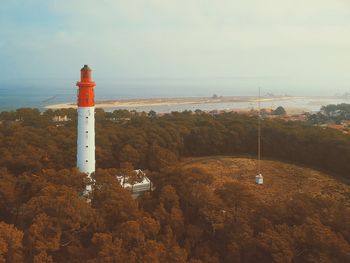 Lighthouse by sea against sky