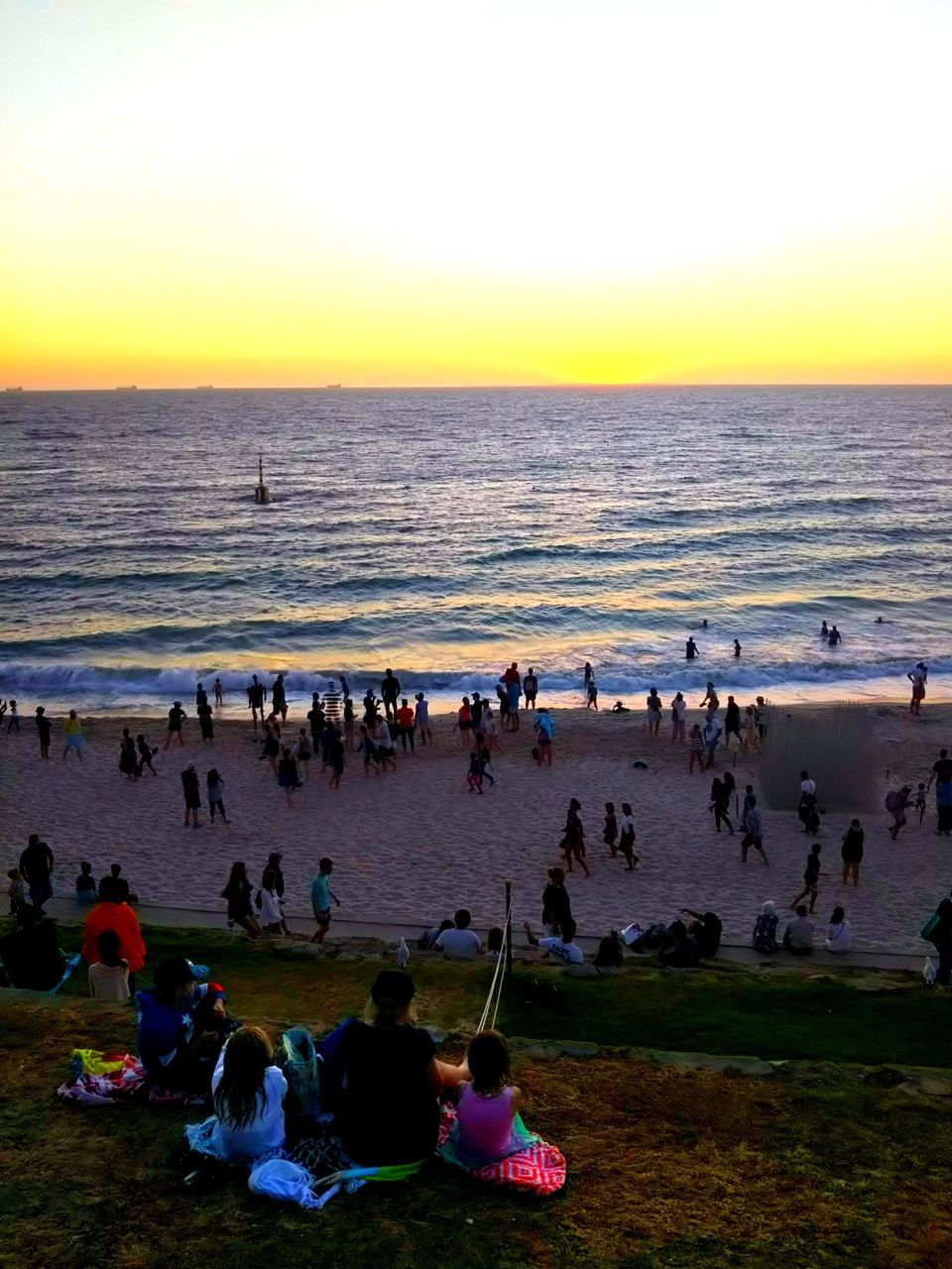 GROUP OF PEOPLE ON BEACH AGAINST SEA