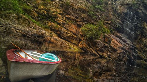 Tilt image of boat moored in lake against rock in forest