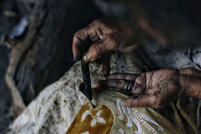 Cropped hands of senior woman designing on textile