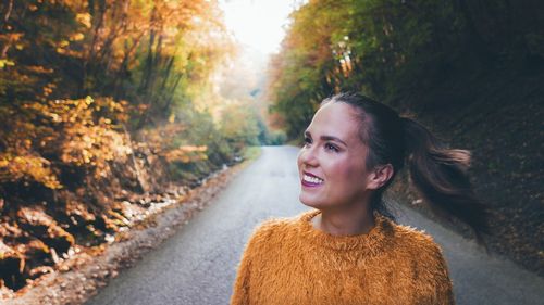 Smiling young woman standing on road 