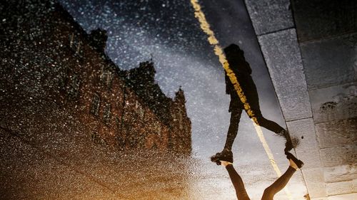 Low section of woman walking on wet street with reflection