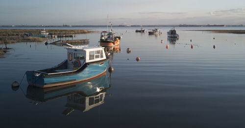 Fishing boats moored in sea against sky