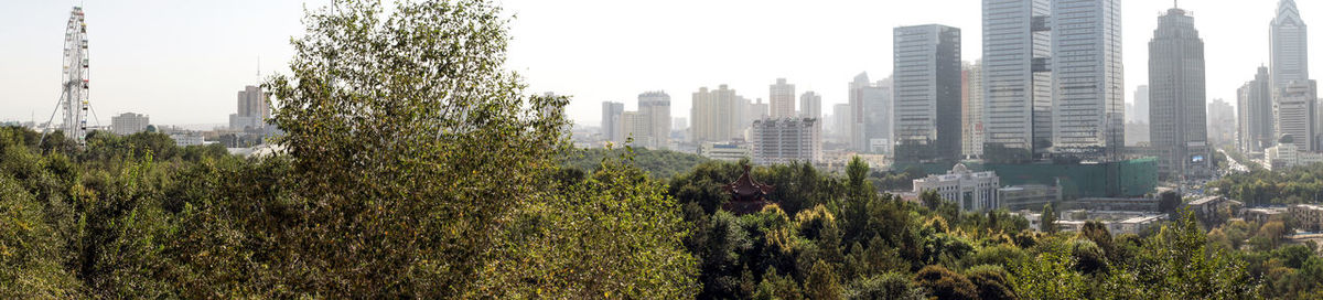 Panoramic view of trees and buildings against clear sky