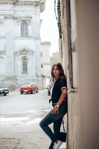 Side view of woman standing by building in city