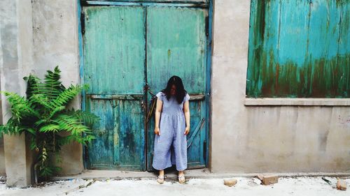 Rear view of woman standing against door of building