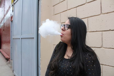 Young woman blowing smoke outdoors