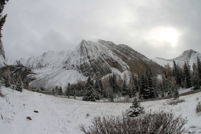 Scenic view of snowcapped mountains against cloudy sky during winter