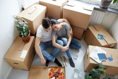 High angle view of couple resting together while having pizza during relocation of new house