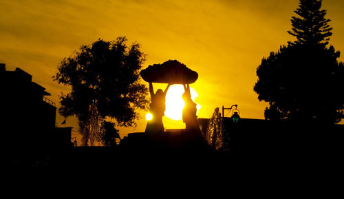 Silhouette trees against orange sky