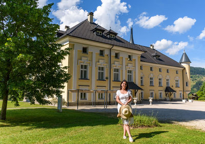 Front view of happy young woman in park in front of beautiful castle in dravograd, slovenia.