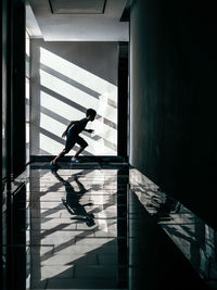 Side view of a boy running in building corridor