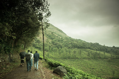 Rear view of people on landscape against sky