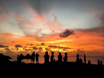 Silhouette people at beach against sky during sunset