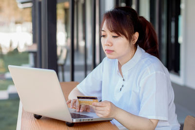 Young woman using mobile phone while sitting on table