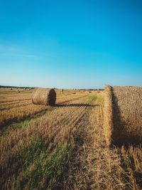 Hay bales on field against clear sky