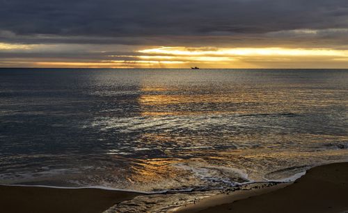 Scenic view of sea against cloudy sky during sunset