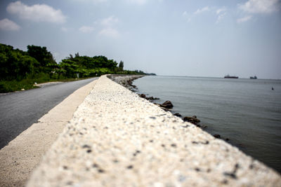 Surface level of road by sea against sky