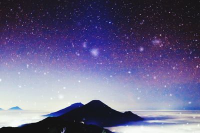 Scenic view of snowcapped mountains against star field at night