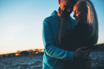 Couple embracing against sea during sunset