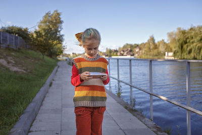 Stylish tween girl with mobile phone walking in the street, kid and gadgets, autumn lifestyle 