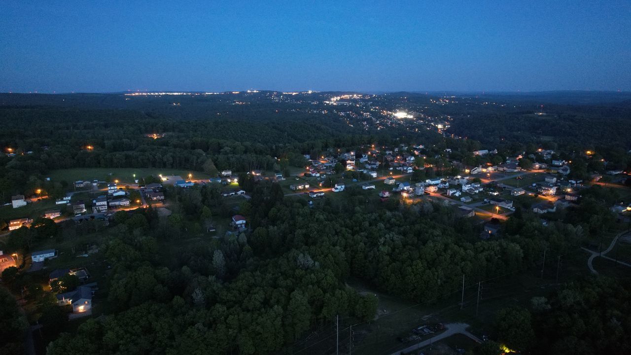 HIGH ANGLE VIEW OF ILLUMINATED TOWNSCAPE AGAINST SKY AT NIGHT