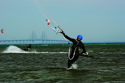 Man with kite on sea against clear sky