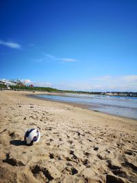 Surface level of sandy beach against blue sky