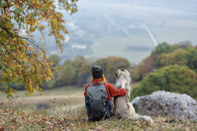 Rear view of woman with dog sitting on plant