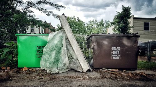 Garbage bin by trees against sky