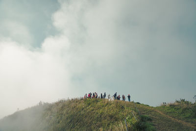 People on mountain against sky