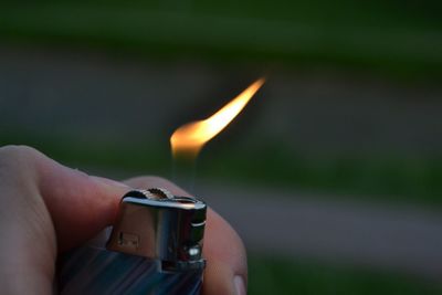 Close-up of hand holding lit cigarette lighter