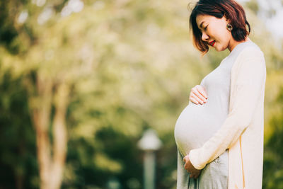 Side view of pregnant woman standing outdoors